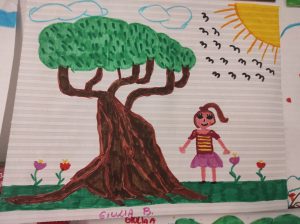 Dibujo de un gran árbol con un tronco grueso, una niña con un vestido, flores, el sol, nubes y pájaros sobre un fondo de papel a rayas.
