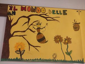 Dibujo de una abeja en la rama de un árbol con girasoles y una colmena sobre papel amarillo.